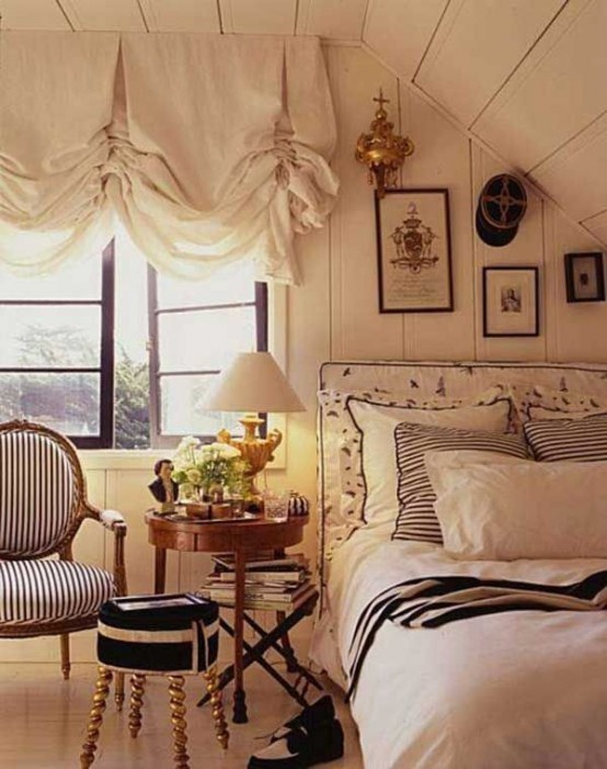 a neutrla vintage bedroom clad with wood, an upholstered bed, vintage chairs and a nightstand plus a ruffle curtain