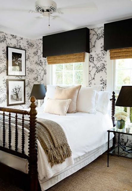 a stylish bedroom with printed wallpaper, catchy shades, a black forged bed and black lamps