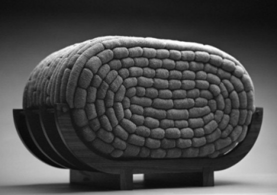 a creative curved seat with a crocheted filled is a very catchy and non-typical furniture piece