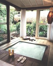 a jacuzzi with a deck around it, some lamps and candles plus sliding doors that allow making the spa indoor or outdoor
