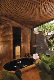 a sunken bathtub with a wooden deck, an outdoor shower next to it and a roof over the tub make up a chic zen-inspired oasis