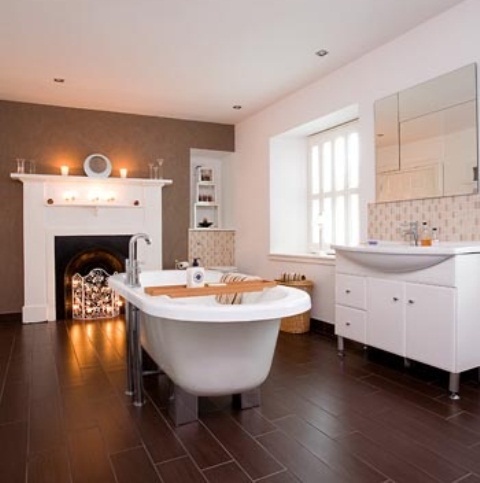 a contrasting bathroom with a faux fireplace with lights, a clawfoot bathtub, white storage units and shelves and a mirror