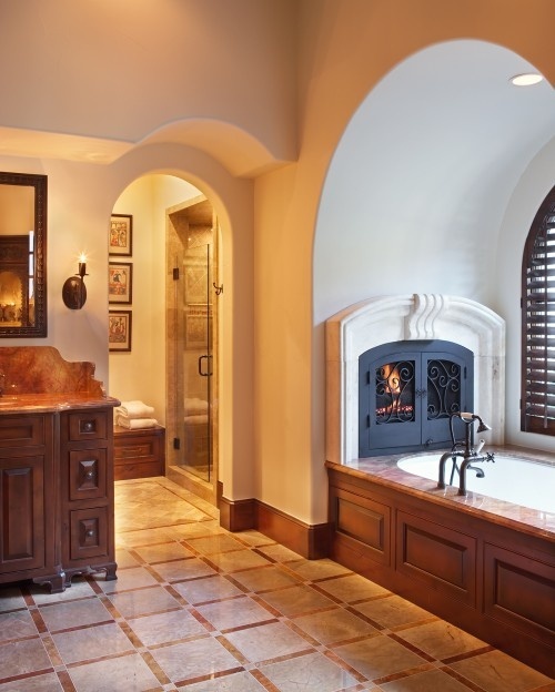 a vintage bathroom with vintage stained furniture, a bathtub clad with wood and a fireplace with a metal wrought iron door is a chic and refined idea