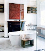 a stylish bathroom with a vintage fireplace, an oval free-standing tub, a statement artwork, a wooden bench and a wooden stool is great