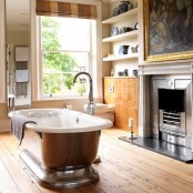 a chic bathroom with a wooden floor, metal fireplace, a metal clad bathtub, open shelves and cabinets for storage