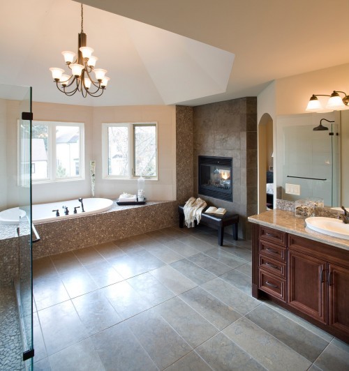 a modern farmhouse bathroom with a sunken bathtub by the window, a built-in fireplace, a stained vanity with a mirror and a shower enclosed in glass