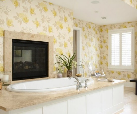 a light-filled bathrom with florla wallpaper, a bathtub clad with tiles, a large fireplace in front of it is a lovely idea and an oasis of relaxation