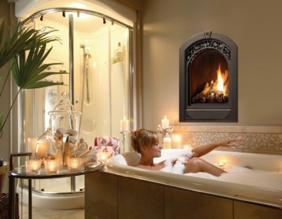 a refined bathroom with a lit up shower, a built-in fireplace, a bathtub clad with large scale tiles and a glass table with candles