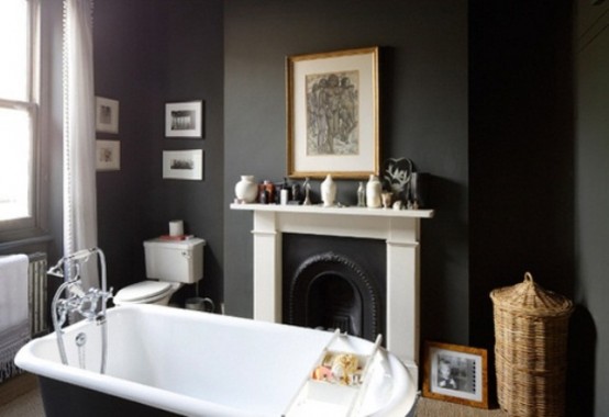 a moody black bathroom with a vintage fireplace and a mantel, a gallery wall, a black vintage bathtub and baskets for storage