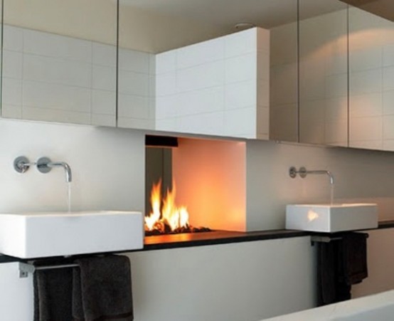 a modern neutral bathroom with a mirror cabinet, a fireplace, a vanity with sinks and dark towels