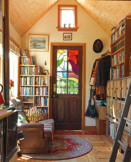 a small and cozy reading space with lots of bookshelves, a leather sofa and some windows plus a door with stained glass that adds special vintage charm to the space