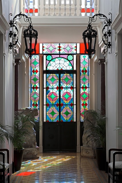 a beautiful vintage entryway with fantastic stained glass doors that fill the space with light and color and with beautiful black pendant lamps