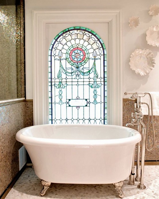 an eclectic bathroom with a shiny shower space, an arched window with stained glass and a small oval bathtub next to it is cool