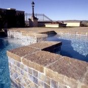 a pool of two parts with a stone deck and neutral tiles is a great idea for outdoors, a great space to spend time on a hot day