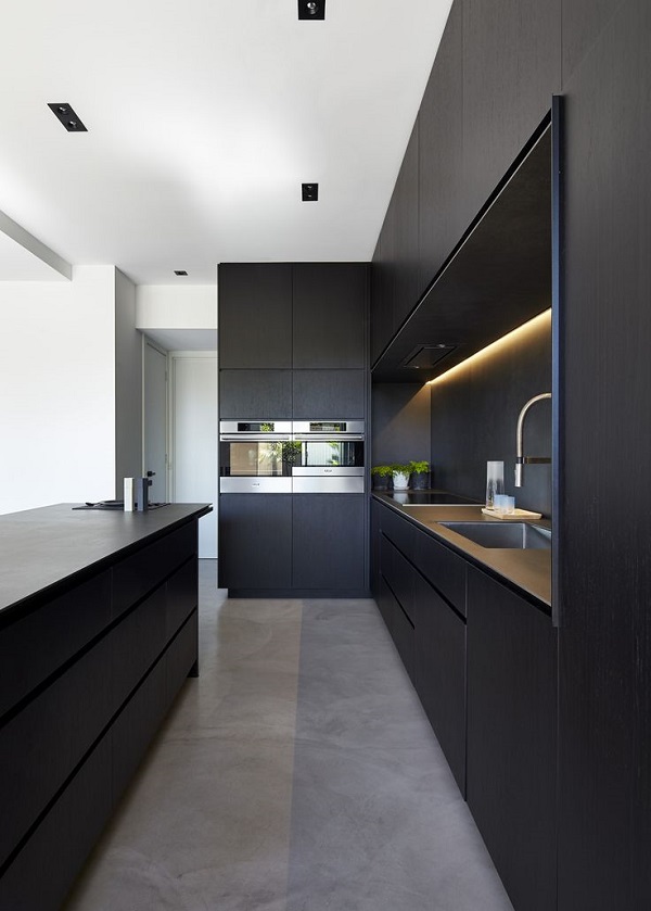 a refined black minimalist kitchen with sleek cabinets, a matching kitchen island, a black backsplash and built in lights