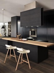 a matte black kitchen with sleek cabinets and all the appliances hidden, with a black kitchen island with a stained countertop and a catchy hood with lights