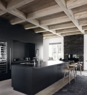 a black minimalist kitchen with sleek cabinets and a kitchen island, a light-stained wooden ceiling and wooden stools to refresh the space