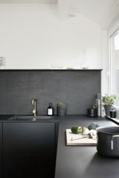 a Scandinavian kitchen with black cabinets, only lower ones, and color block walls – white ones with a black backsplash