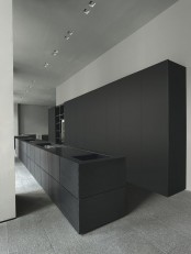 an ultra-minimalist black and grey kitchen with matte cabinets and a kitchen island, all the appliances hidden for an ultra-minimal look