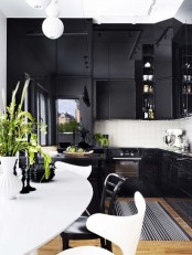a matte and glossy black kitchen with a white tile backsplash, a white oval table and black and white chairs, a printed rug and a pendant lamp
