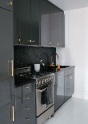 a glossy black kitchen with black chevron tiles on the backsplash and gold fixtures is a cool and chic idea in a classic color