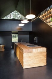 a catchy minimalist black kitchen with a light-stained kitchen island that refreshes the space and pendant lamps over it