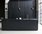 a minimalist matte black kitchen with sleek cabinets, a large kitchen island, pendant lamps and a white floor and a glazed wall for a fresher look