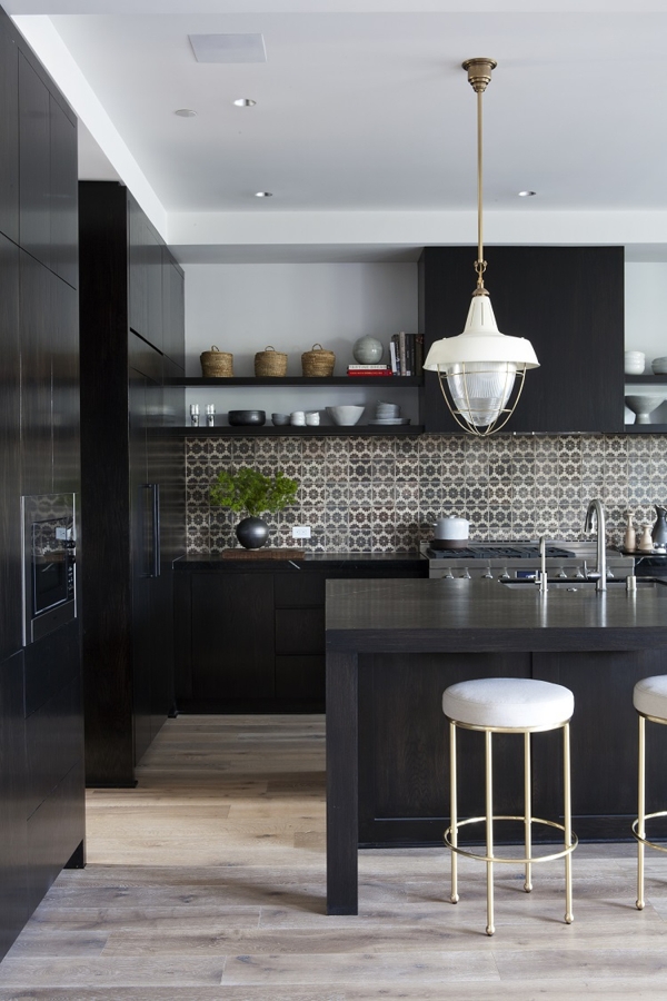 a black kitchen with a printed black and white tile backsplash, open shelves, a large kitchen island, white stools and white pendant lamps