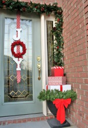 an evergreen garland with pinecones and lights, a letter sign in red and an urn with a stack of Christmas gift boxes