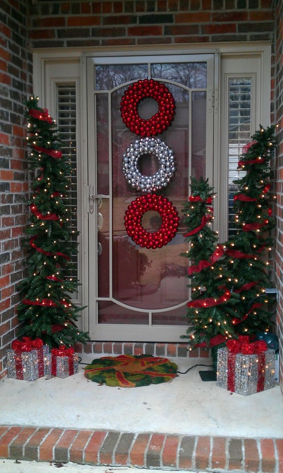 cozy front door Christmas styling with red and silver Christmas ornament wreaths, tree Christmas trees with red ribbons and lights, silver lit up gift boxes