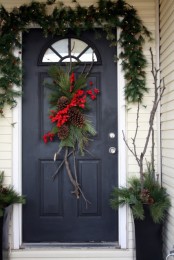 natural Christmas front door decor with evergreens, lights, pinecones, twig and red berries looks very cozy