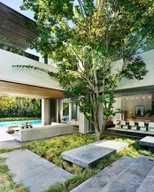 greenery and a single large tree growing in the courtyard right in the center of the house create a cool private space
