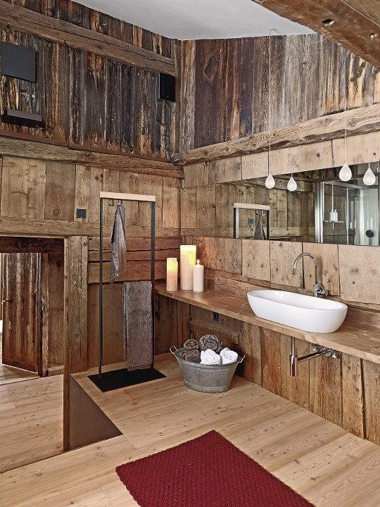 a bathroom fully clad with rough wood, with pendant lamps and an oval sink is a stylish space to be