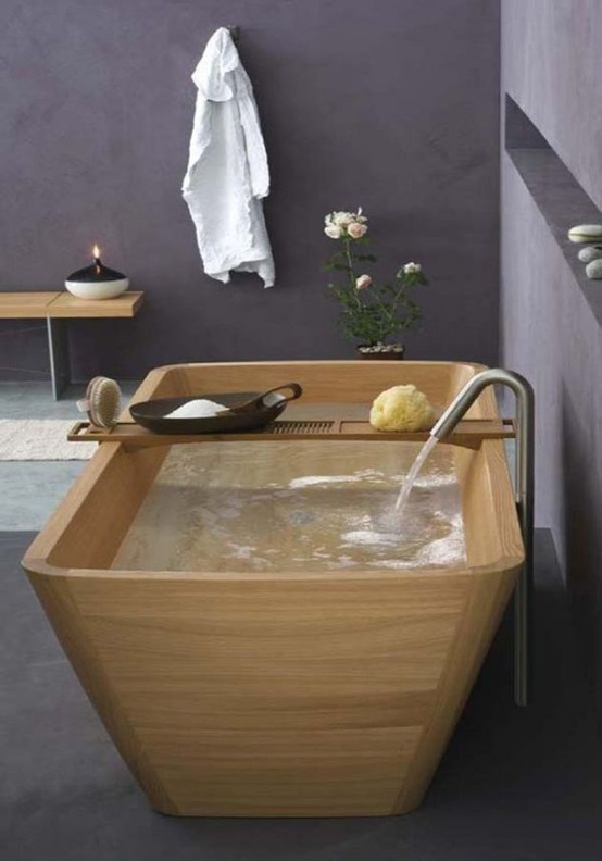 a contemporary bathroom fully done with concrete, with a wooden bathtub and a matching bench, with neutral textiles feels relaxed and zen-like