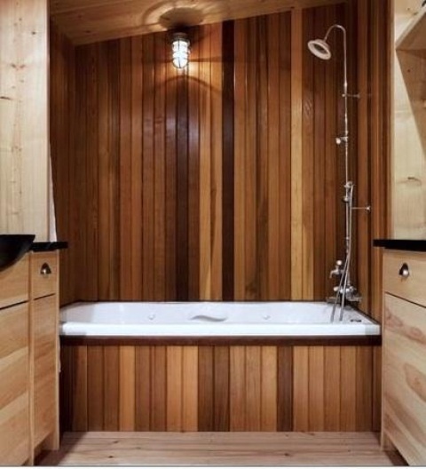 a modern bathroom with a bold reclaimed wood wall and a bathtub, with neutral stained vanities is cozy and welcoming