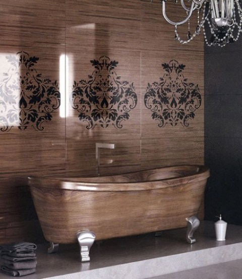 a refined bathroom with a stained wood wall with stencils and a wooden bathtub, a crystal chandelier and dark towels is bold and cool