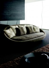 a grey curved loveseat with lots of pillows is a cool idea for many modern spaces, outdoor or indoor ones