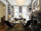 a stylish home office with grey walls, a white shelving unit, a fireplace and black leather chairs