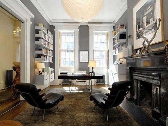 a stylish home office with grey walls, a white shelving unit, a fireplace and black leather chairs
