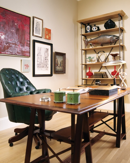 an eclectic home office with a wooden trestle desk, a metal and wood shelving unit and a gallery wall