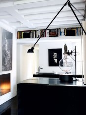 a minimalist monochromatic home office with a black desk, an open bookshelf, a fireplace and lots of artworks