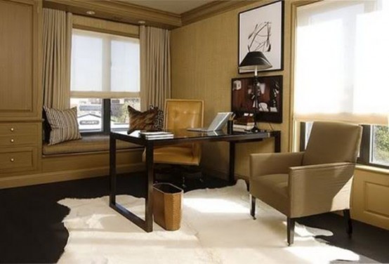 a modern home office done in tan and earthy shades, built-in furniture, a black desk and a chair plus artworks