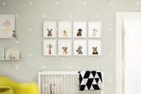 a pretty nursery with grey star printed walls, a white crib with black and white bedding, a yellow chair, a mini gallery wall and some toys