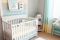 a pastel nursery with grey walls, white and mint colored furniture, pastel bedding and a printed rug plus a striped accent wall