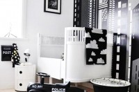 a catchy black and white nursery with an accent wall, a white crib and black and white bedding, a black rug and some black and white toys