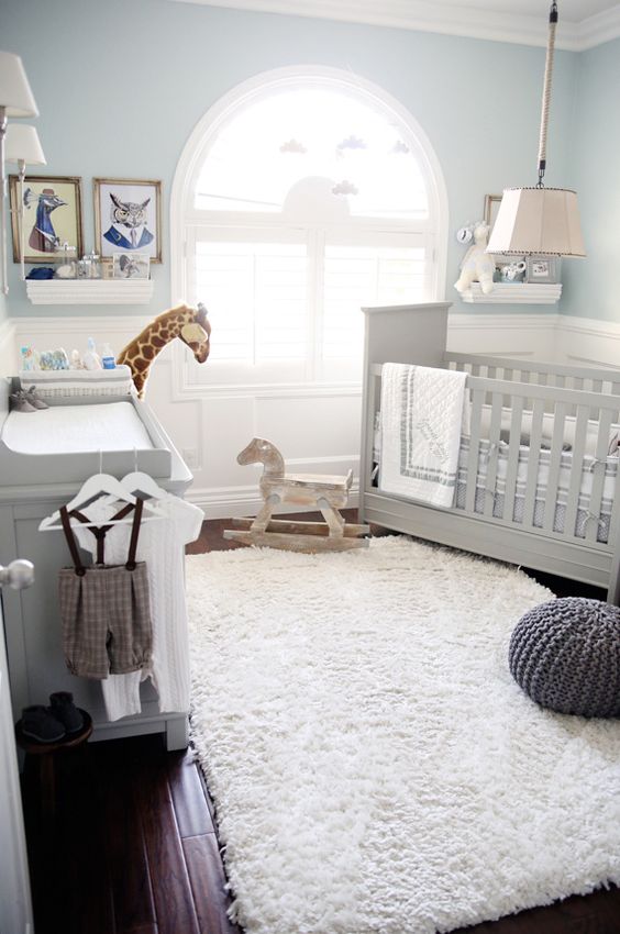 a pretty vintage inspired nursery with light blue walls, grey furniture, neutral bedding, artwork and pendant lamps