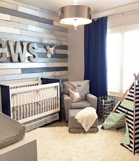 a rustic nursery with a reclaimed wood wall, neutral and contrasting furniture, a teepee and navy curtains