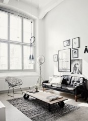 a Scandinavian living room with industrial touches like a leather sofa, a cluster of pendant lamps and a wood table on casters