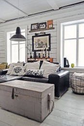 a Scandinavian living room with a black leather sofa, a metal pendant lamp and a wire basket for an industrial feel