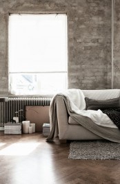 grey brick walls, an uncovered metal radiator and a simple wooden floor create a simple industrial setup